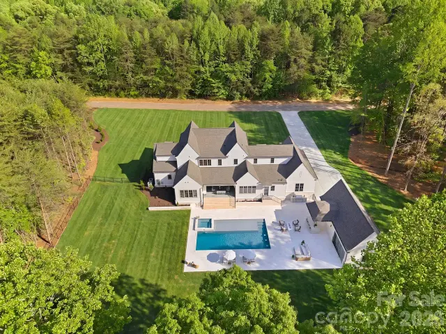 Aerial view of an estate with pool and wooded grounds
